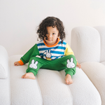 Niño con el conjunto de bambú «Move» de {{5acda3a9b3eeac56b7846cf24e8ac4d8}, compuesto por una sudadera con motivo de bicicleta y unos pantalones de chándal verdes.