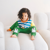 Niño con el conjunto de bambú «Move» de {{5acda3a9b3eeac56b7846cf24e8ac4d8}, compuesto por una sudadera con motivo de bicicleta y unos pantalones de chándal verdes.