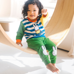 Niño con el conjunto de bambú «Move» de {{5acda3a9b3eeac56b7846cf24e8ac4d8}, compuesto por una sudadera con motivo de bicicleta y unos pantalones de chándal verdes.
