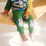 Niño con el conjunto de bambú «Move» de {{5acda3a9b3eeac56b7846cf24e8ac4d8}, compuesto por una sudadera con motivo de bicicleta y unos pantalones de chándal verdes.