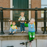 Niño con el conjunto de bambú «Move» de {{5acda3a9b3eeac56b7846cf24e8ac4d8}, compuesto por una sudadera con motivo de bicicleta y unos pantalones de chándal verdes.